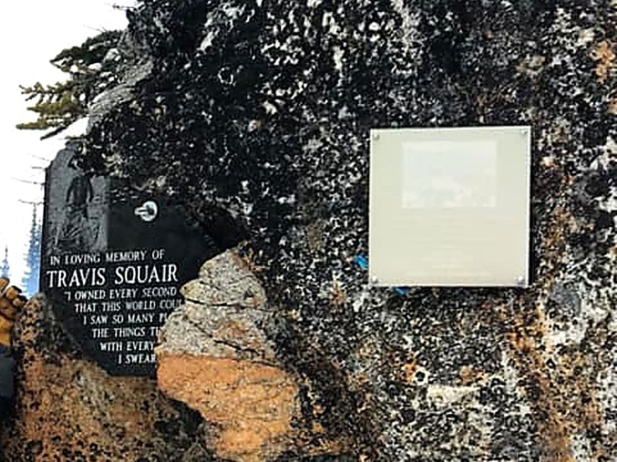 An engraved granite memorial bolted into a mountain rock face